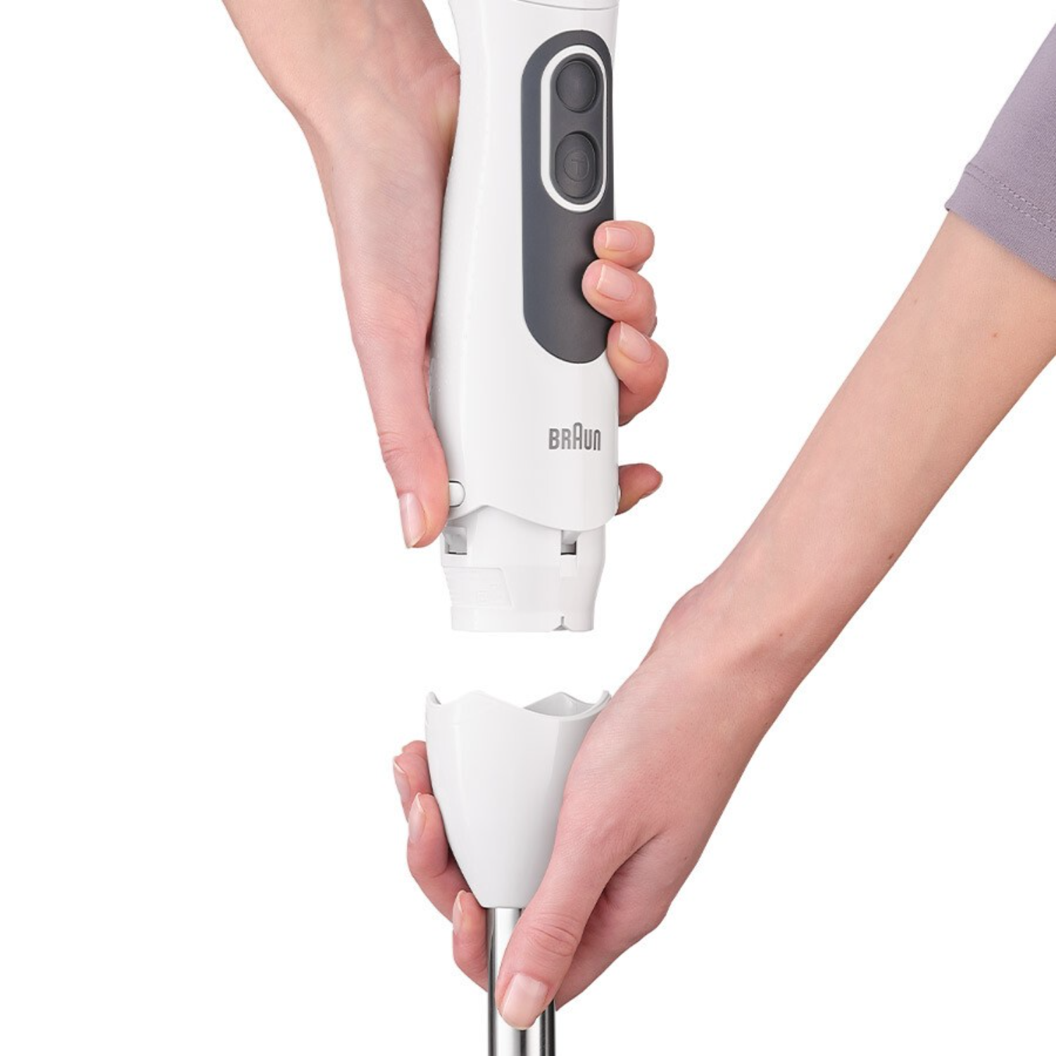 De handen van een persoon die een witte en grijze Braun staafmixer in elkaar zet.