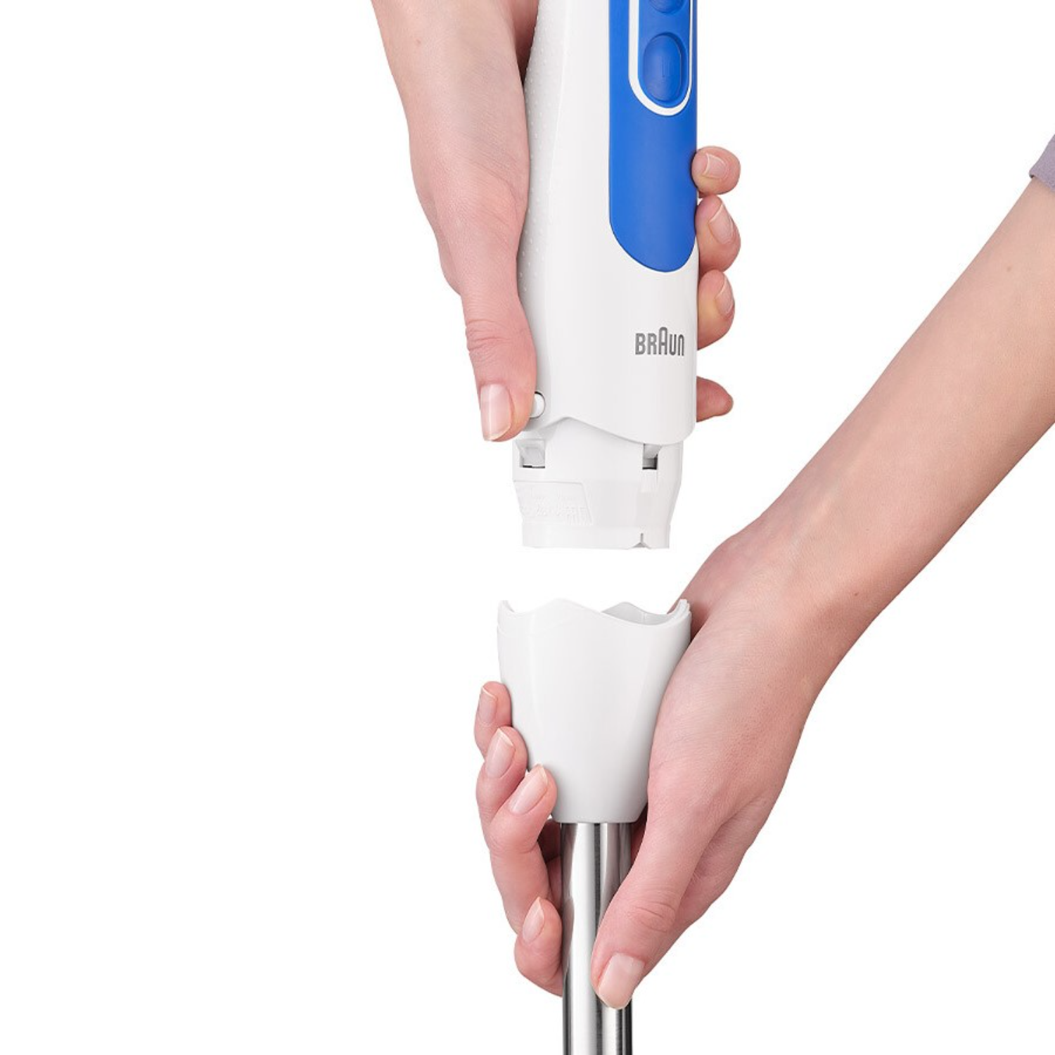 Hands assembling a Braun hand blender, white and blue, on white background.