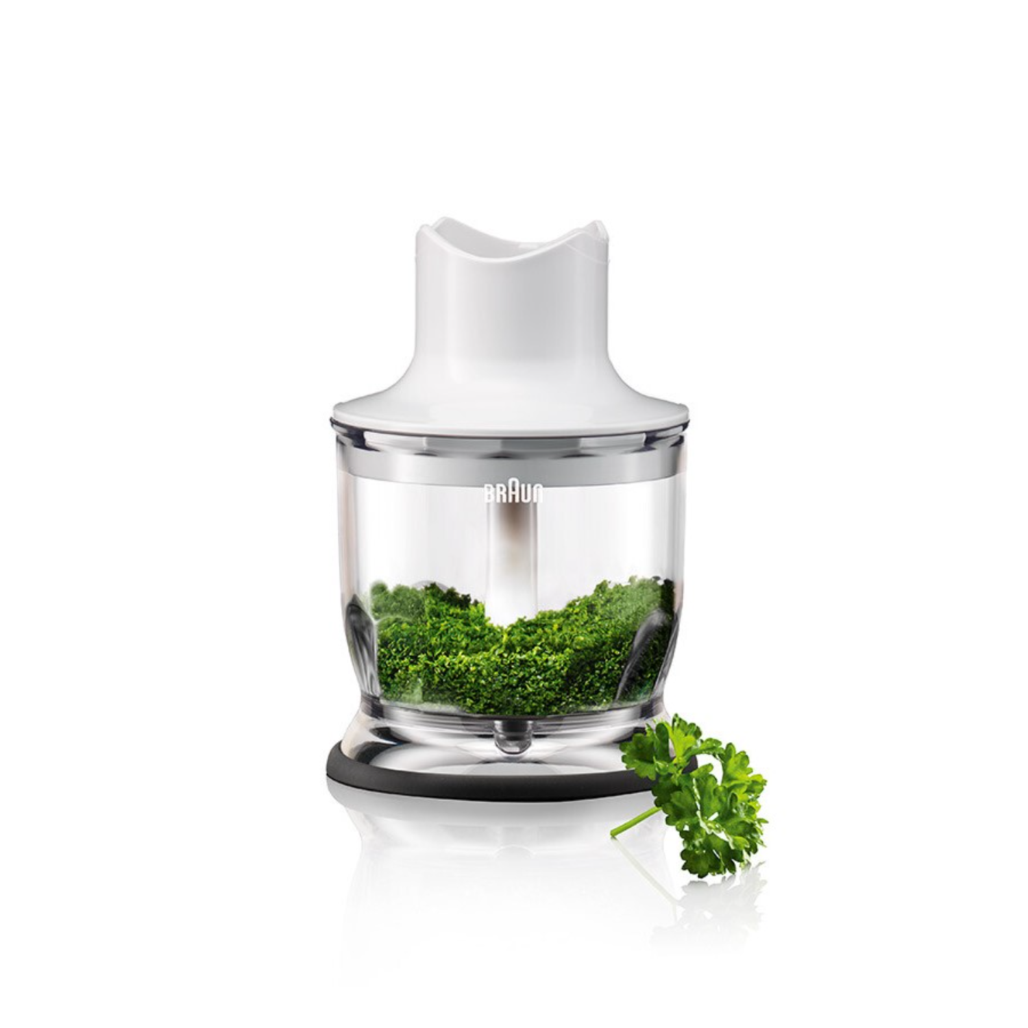 White hand blender with a clear container filled with chopped green herbs. A sprig of parsley is present.