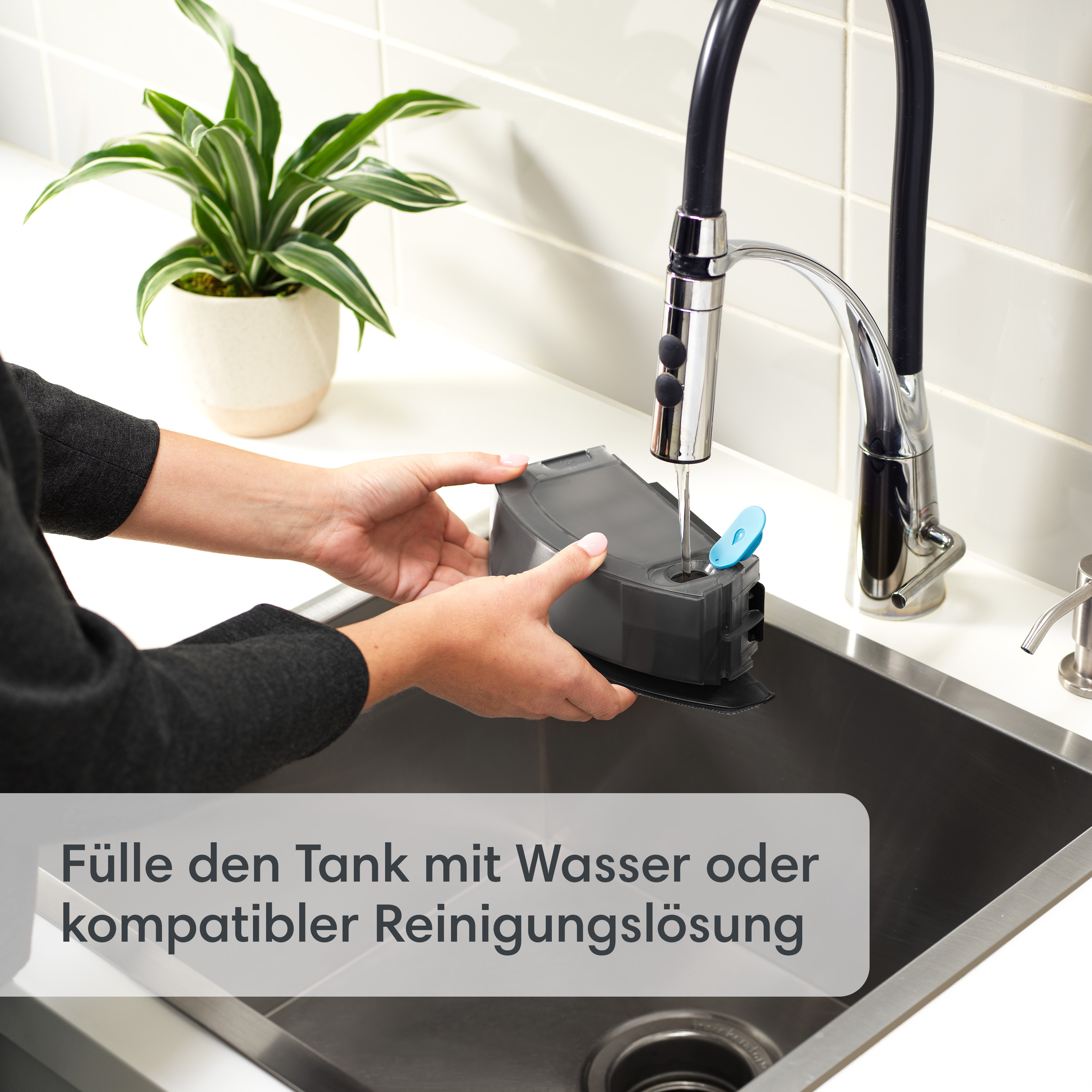 Hände halten einen dunkelgrauen Tank unter einem Wasserhahn. Text über das Befüllen.