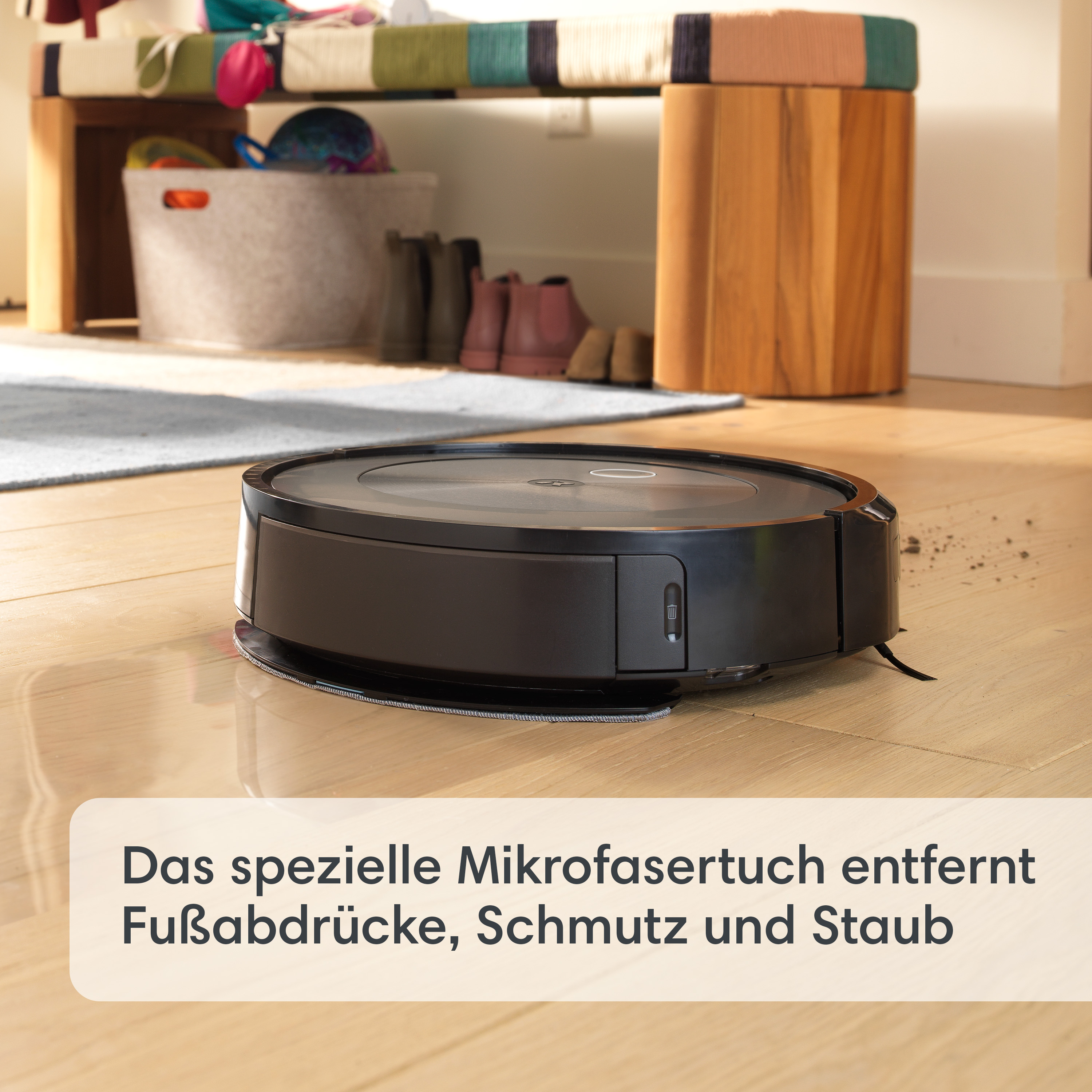Ein schwarzer Roboter-Staubsauger reinigt einen Holzboden. Eine Textüberlagerung in Deutsch ist vorhanden.