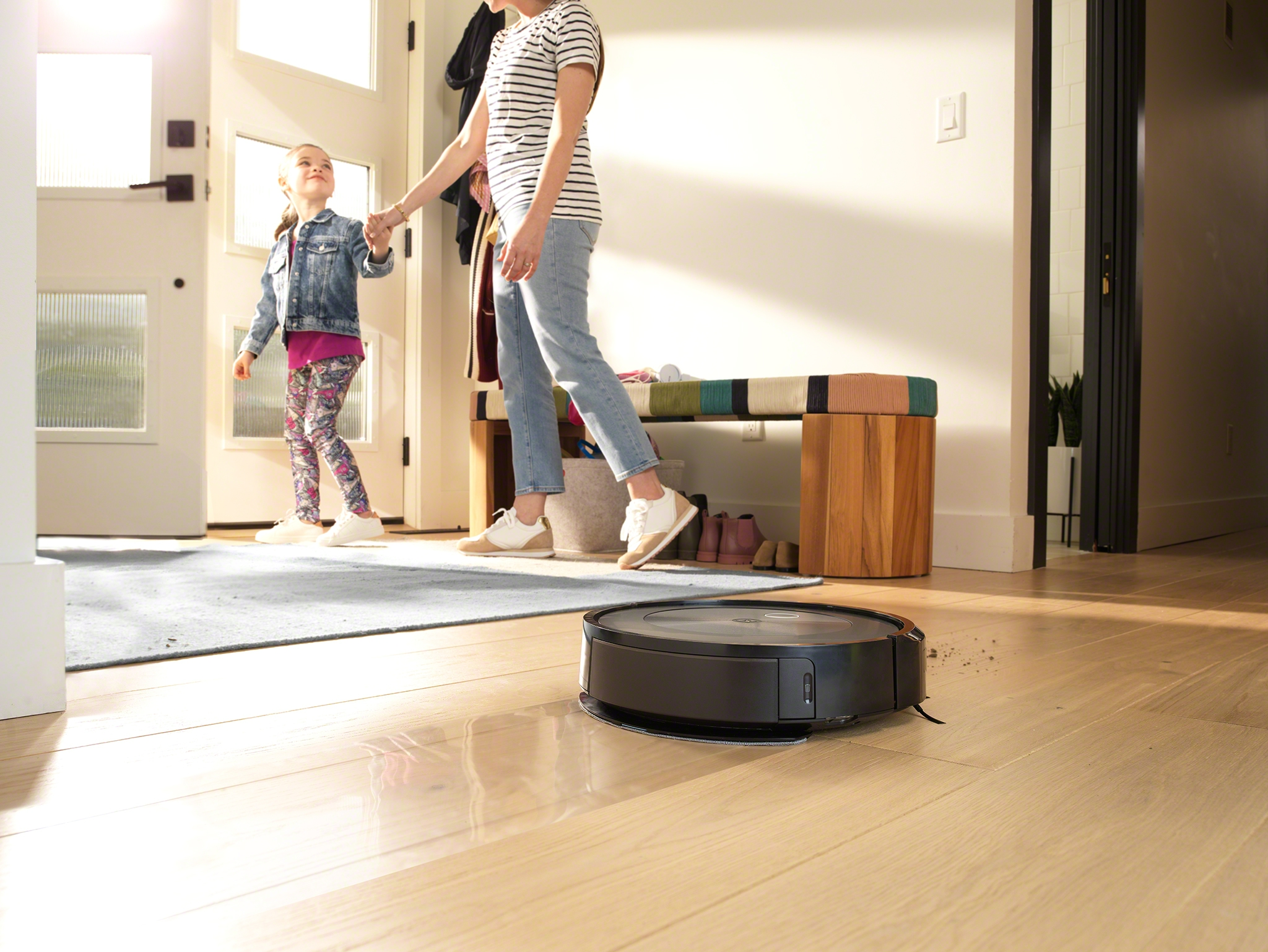 Eine Familie in einem häuslichen Umfeld mit einem Roboter-Staubsauger auf dem Boden.