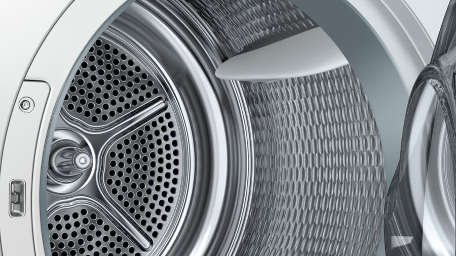 Zbliżenie wnętrza bębna pralki ze stali nierdzewnej z otworami.