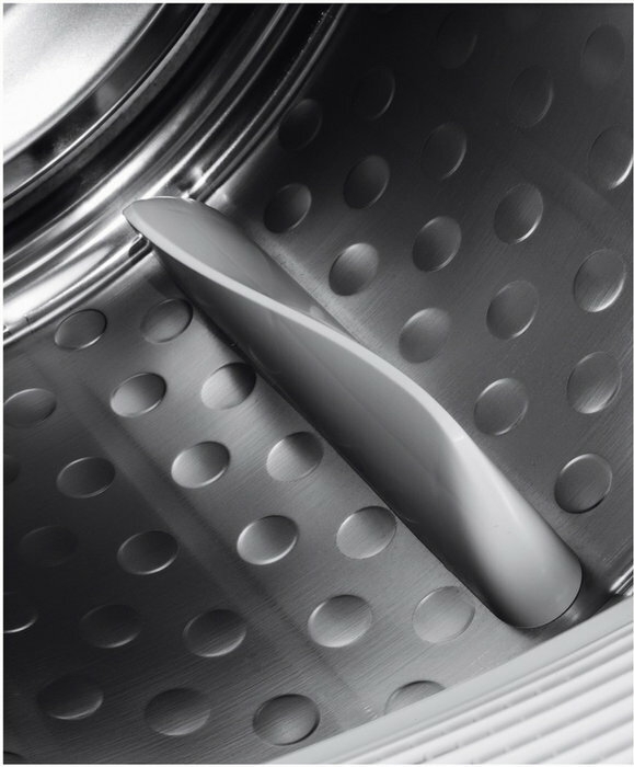 Wnętrze suszarki bębnowej. Metalowy bęben z otworami i szara łopatka.