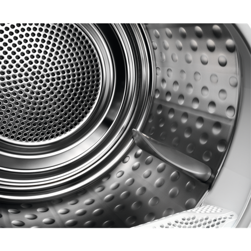 Wnętrze srebrnego bębna pralki z perforacjami i łopatką.