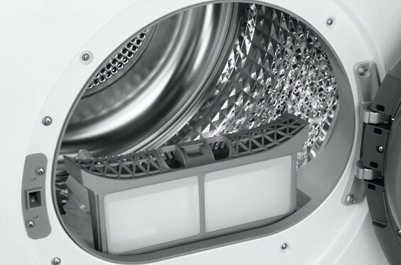 Zbliżenie wnętrza pralki, z filtrem pośrodku.