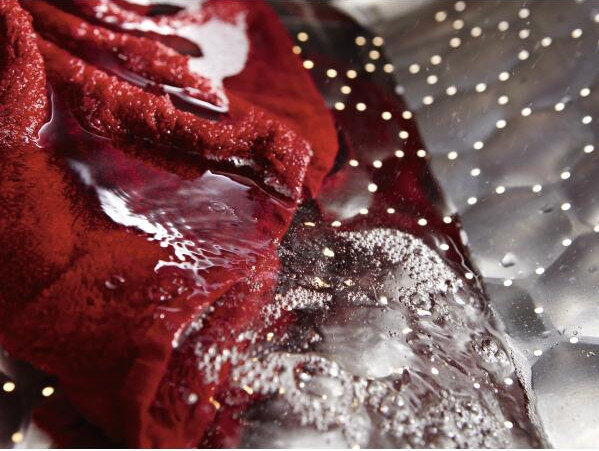 Zbliżenie czerwonej tkaniny w pralce z wodą i bąbelkami.