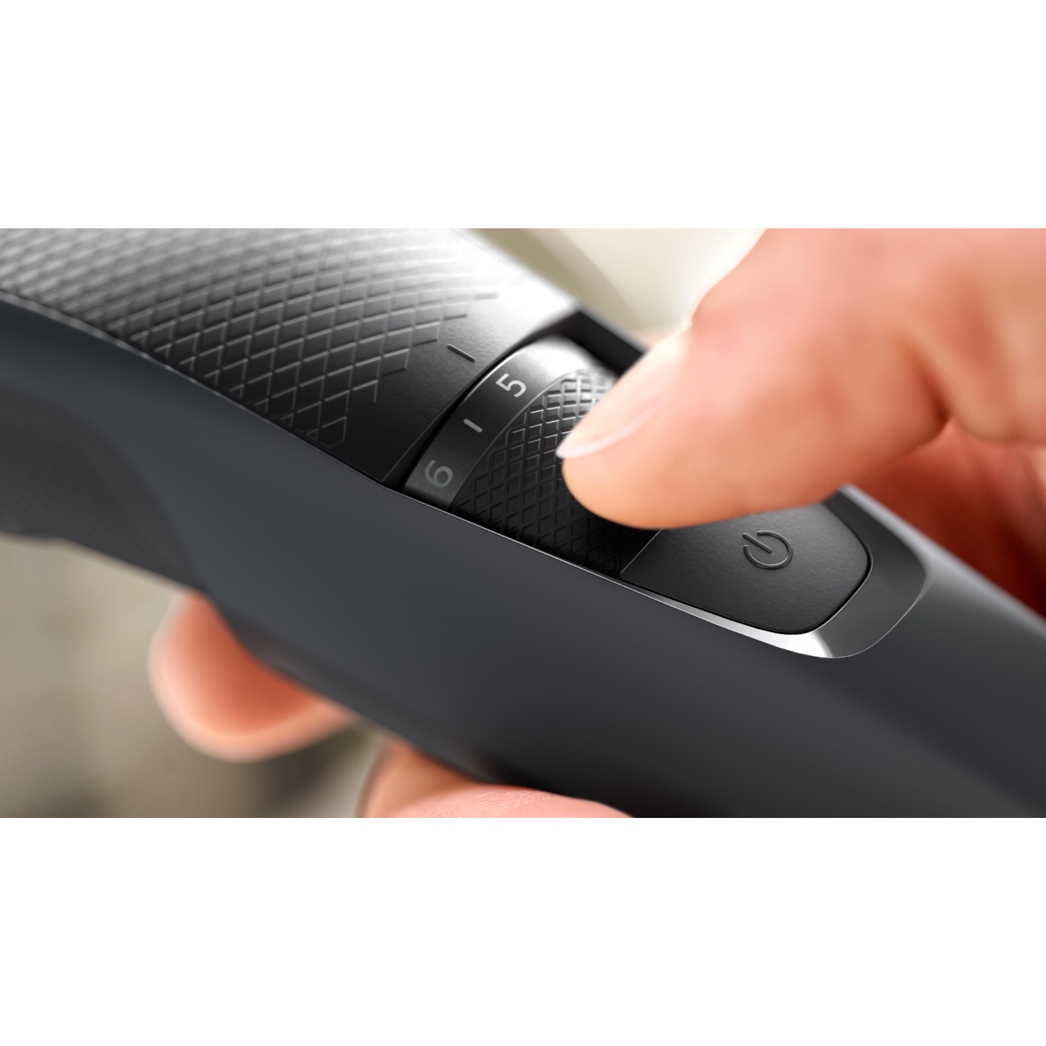 A hand adjusting a black electric hair clipper, showing the numbered settings.