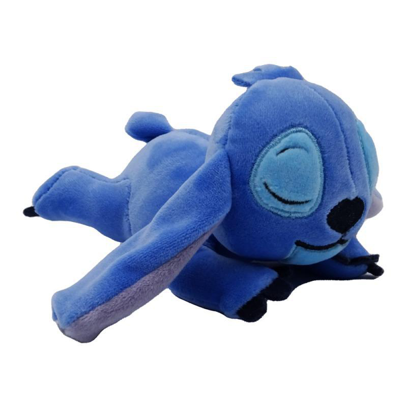 Blaues Stitch-Plüschtier liegt mit geschlossenen Augen auf weißem Grund.