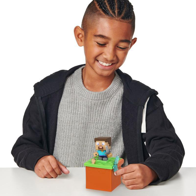 Junge lächelt über eine Minecraft-Spielfigur auf einem Tisch.
