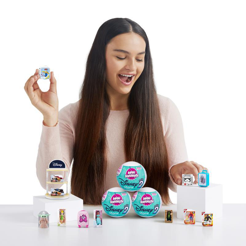 Eine Frau und Disney Mini Brands. Disney Mini Brands werden ausgestellt, umgeben von der Frau.