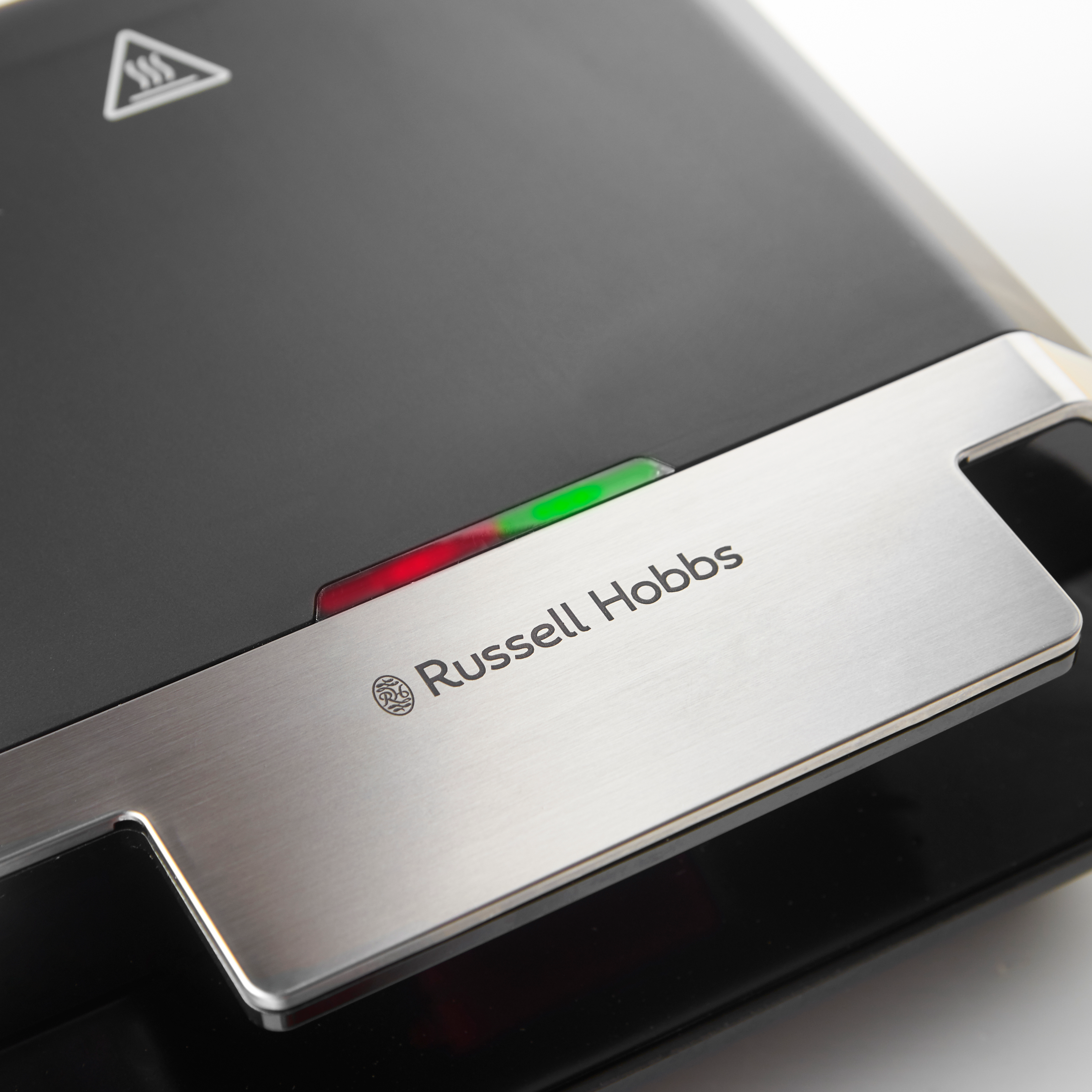 Közelkép egy fekete Russell Hobbs szendvicssütőről. Zöld és piros jelzőfények láthatók.