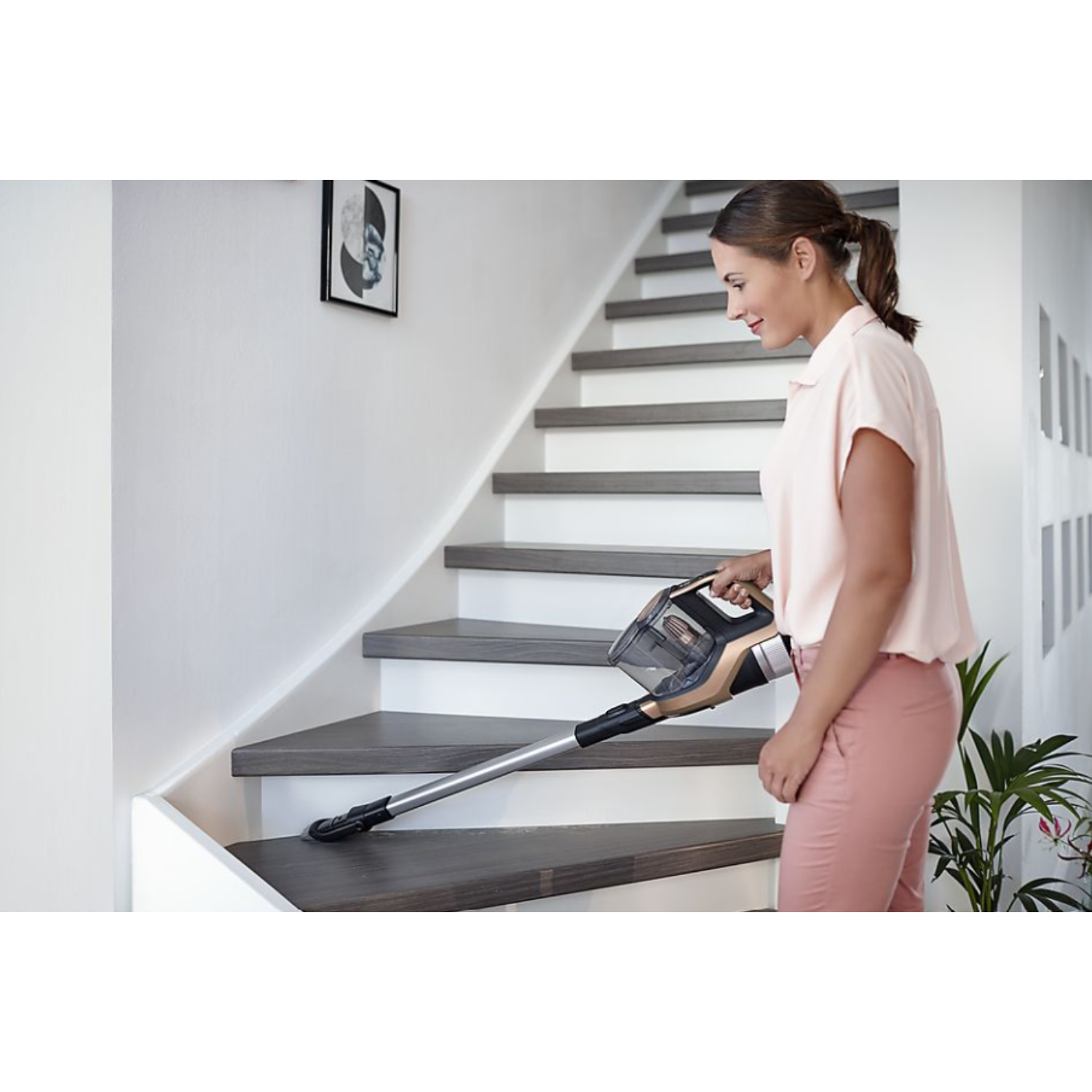 Een vrouw die trappen stofzuigt met een handstofzuiger.