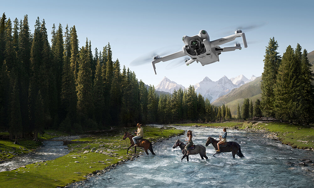 Dron lata nad rzeką. Ludzie na koniach przekraczają rzekę.