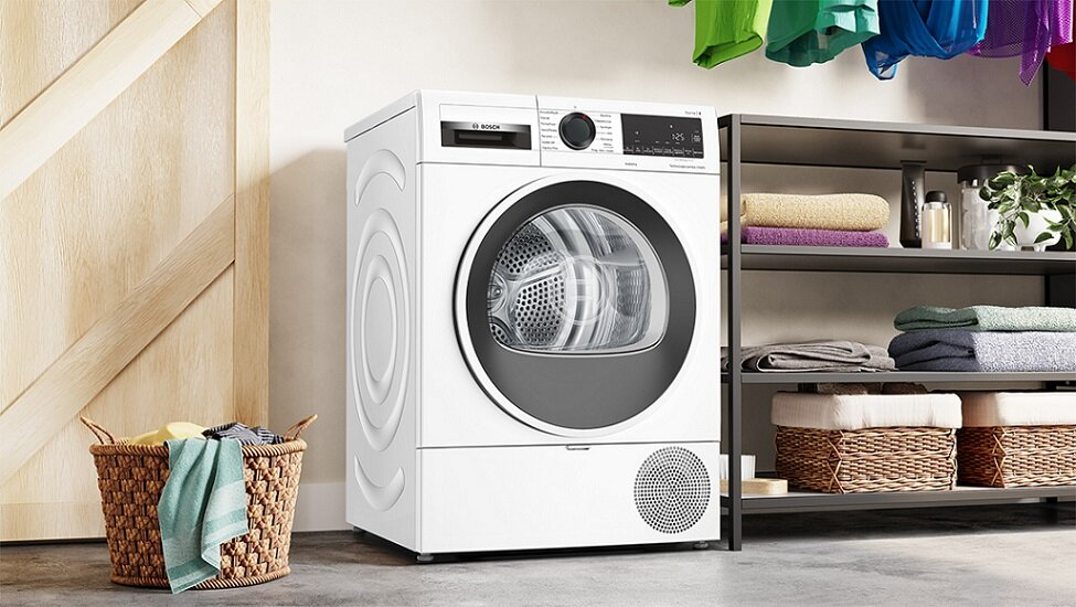 Biała pralka z koszem na pranie obok, w pralni.