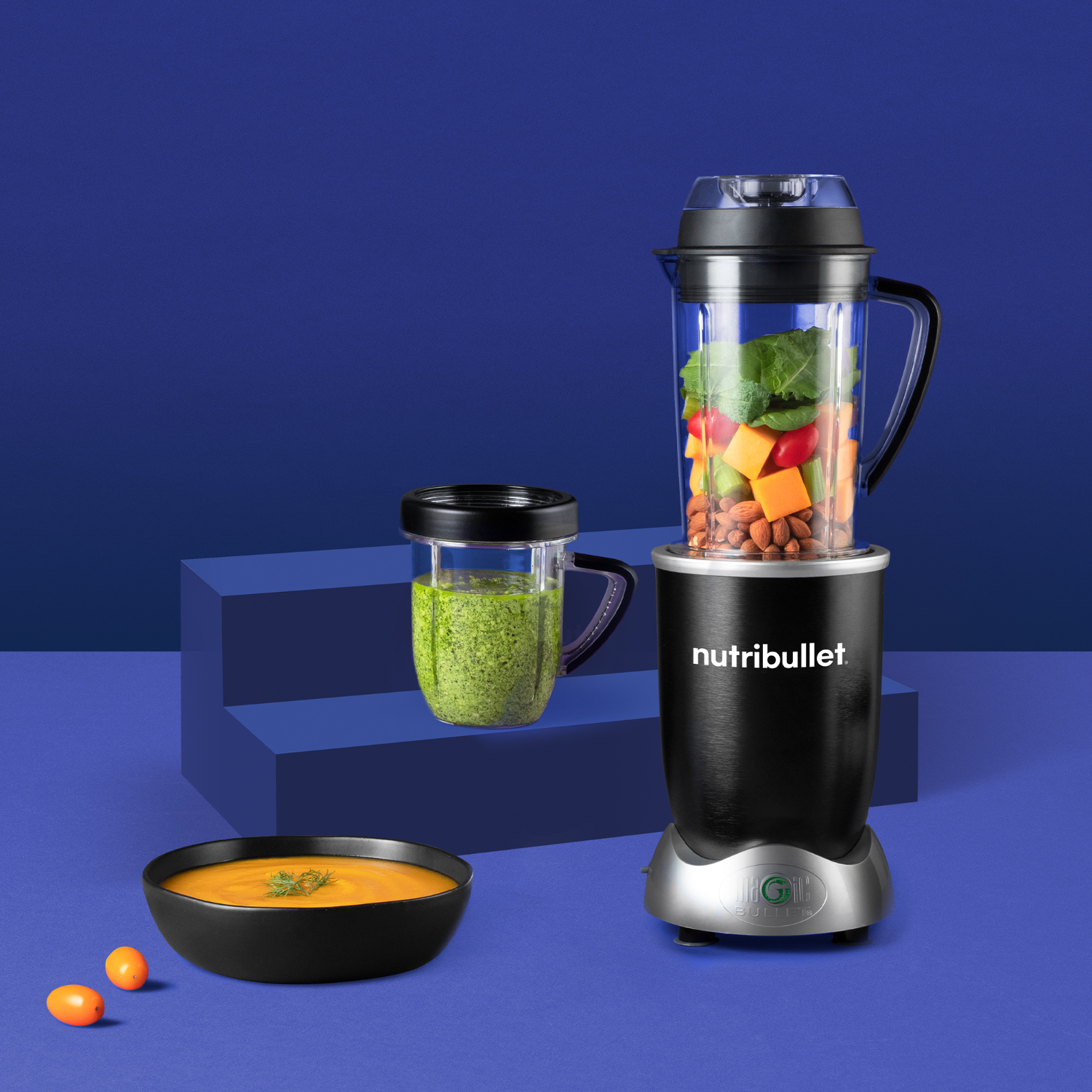 A blender with food inside, a small cup and bowl with soup.