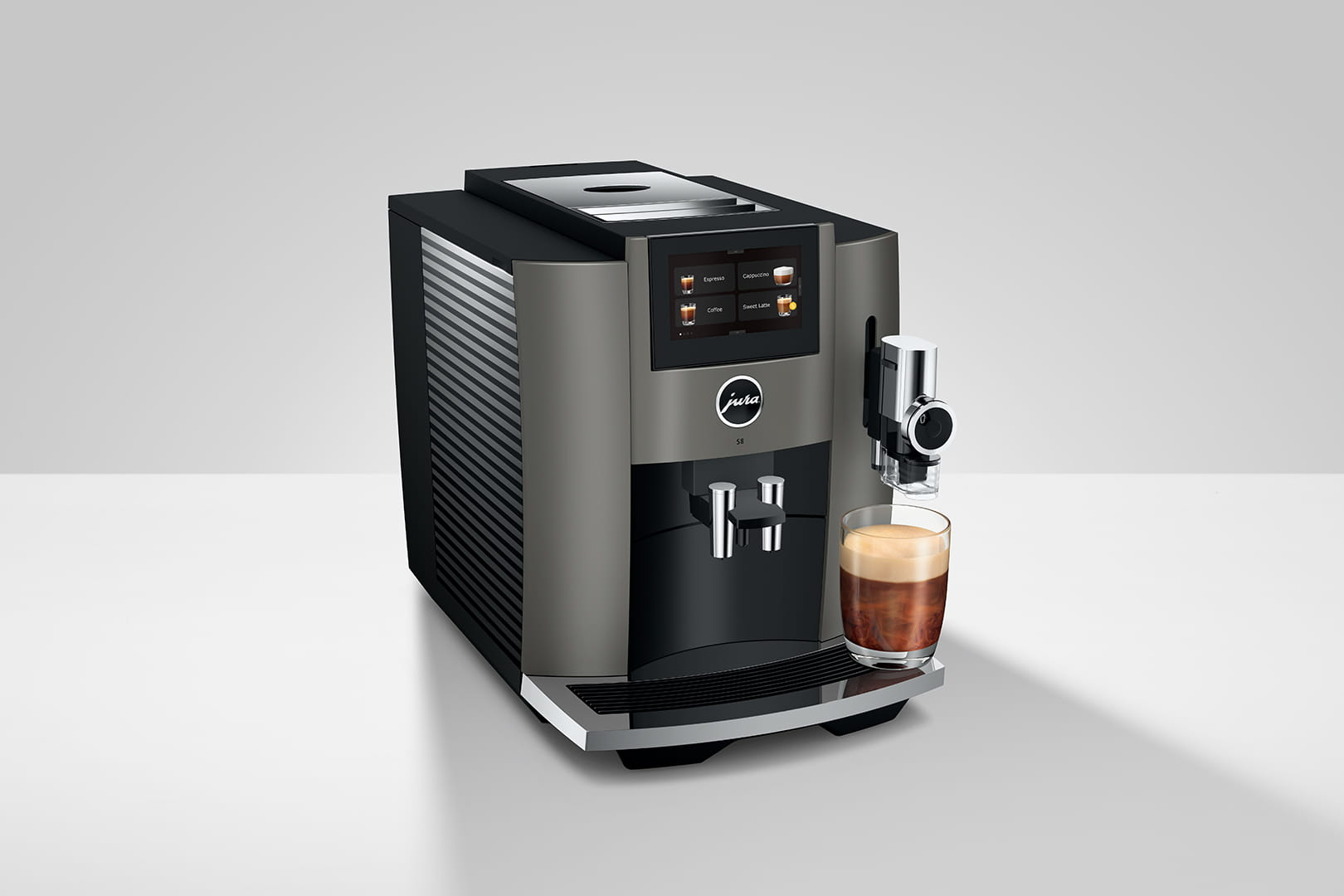 Macchina per espresso grigia con un bicchiere di caffè. La macchina ha un touchscreen e un beccuccio.