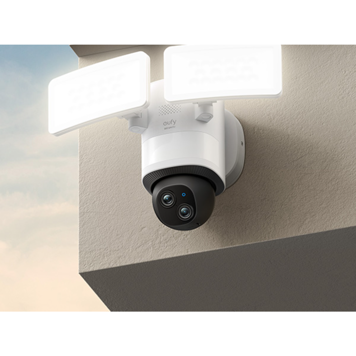 White outdoor security camera with two lights on a wall. Black camera lens.