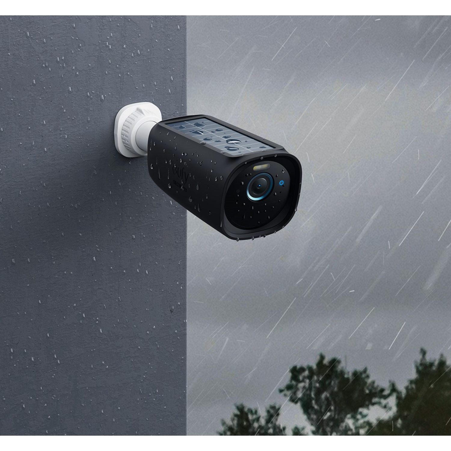 A black security camera mounted on a wall, with rain.