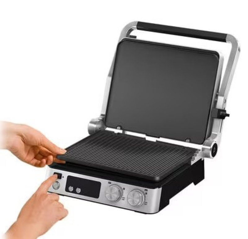 Osoba naciska przycisk zasilania na srebrnym grillu z czarną powierzchnią do gotowania.
