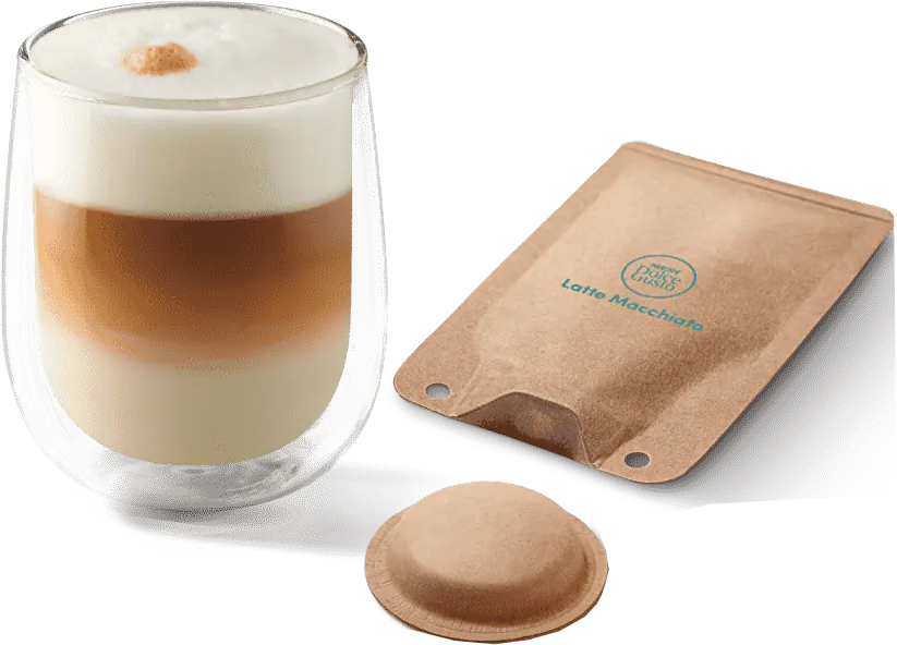 Un bicchiere di latte macchiato a strati con una capsula di caffè e una confezione, il tutto su sfondo bianco.