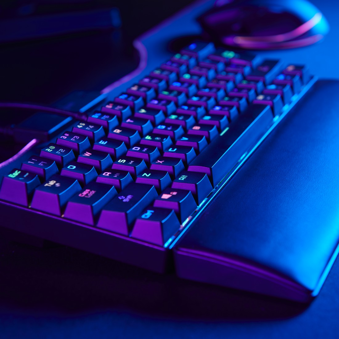RGB világítású gaming billentyűzet, sötét háttér, billentyűk és csuklótámasz látható.