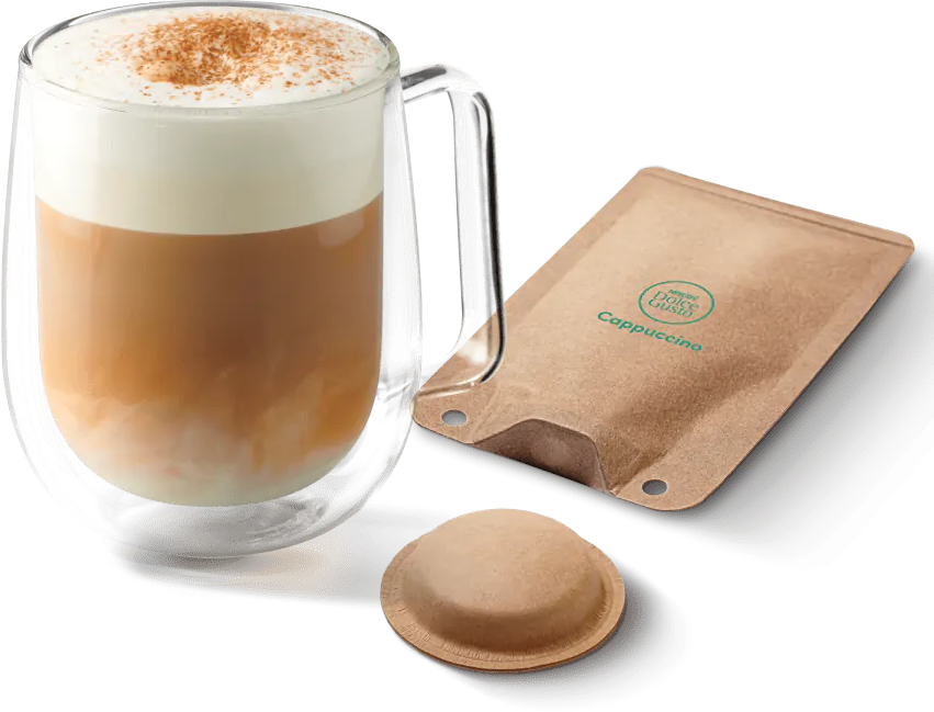 Cappuccino in tazza di vetro, con cialda e bustina di caffè, spolverato di cannella.