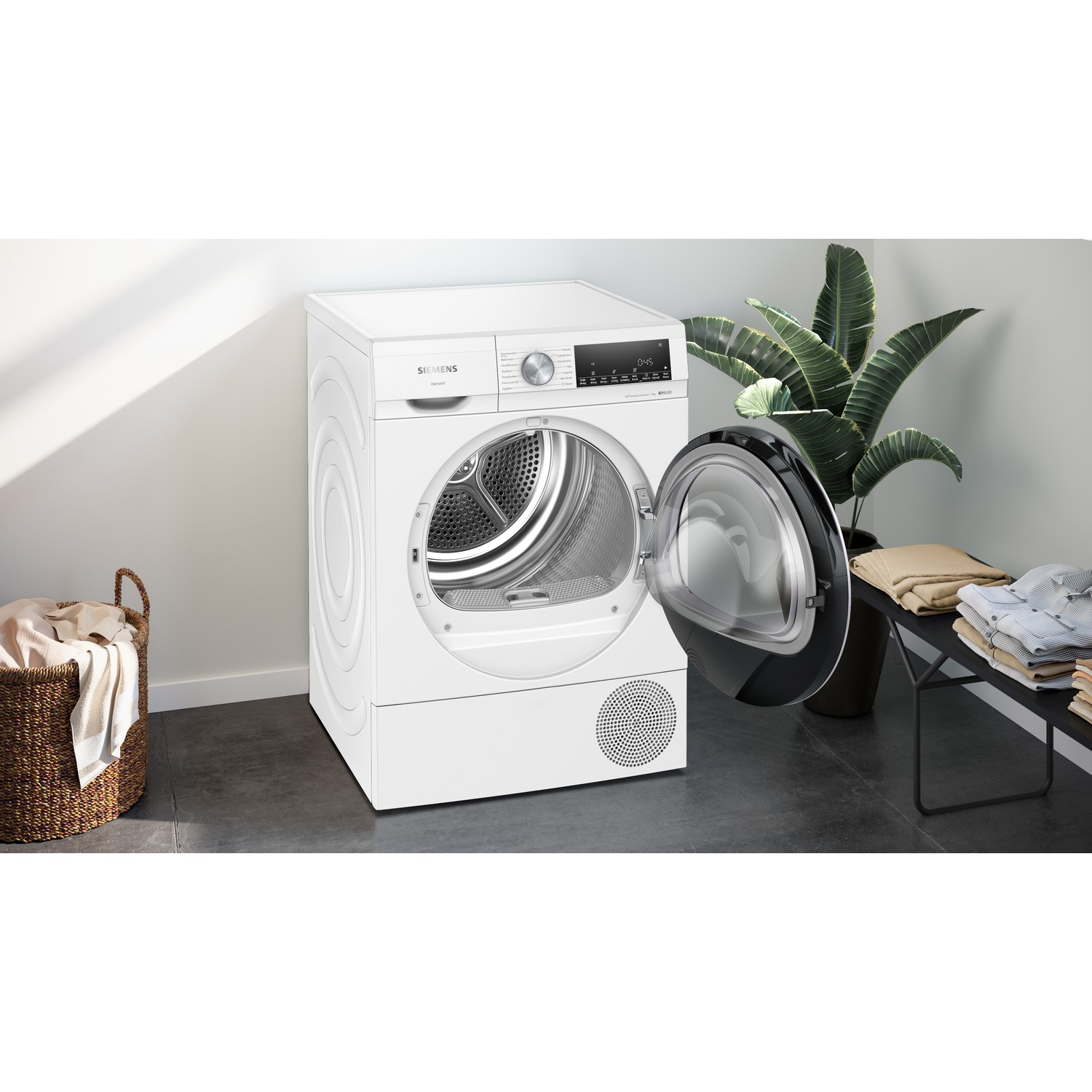 A white dryer with an open door, revealing the drum, with a stack of folded clothes.