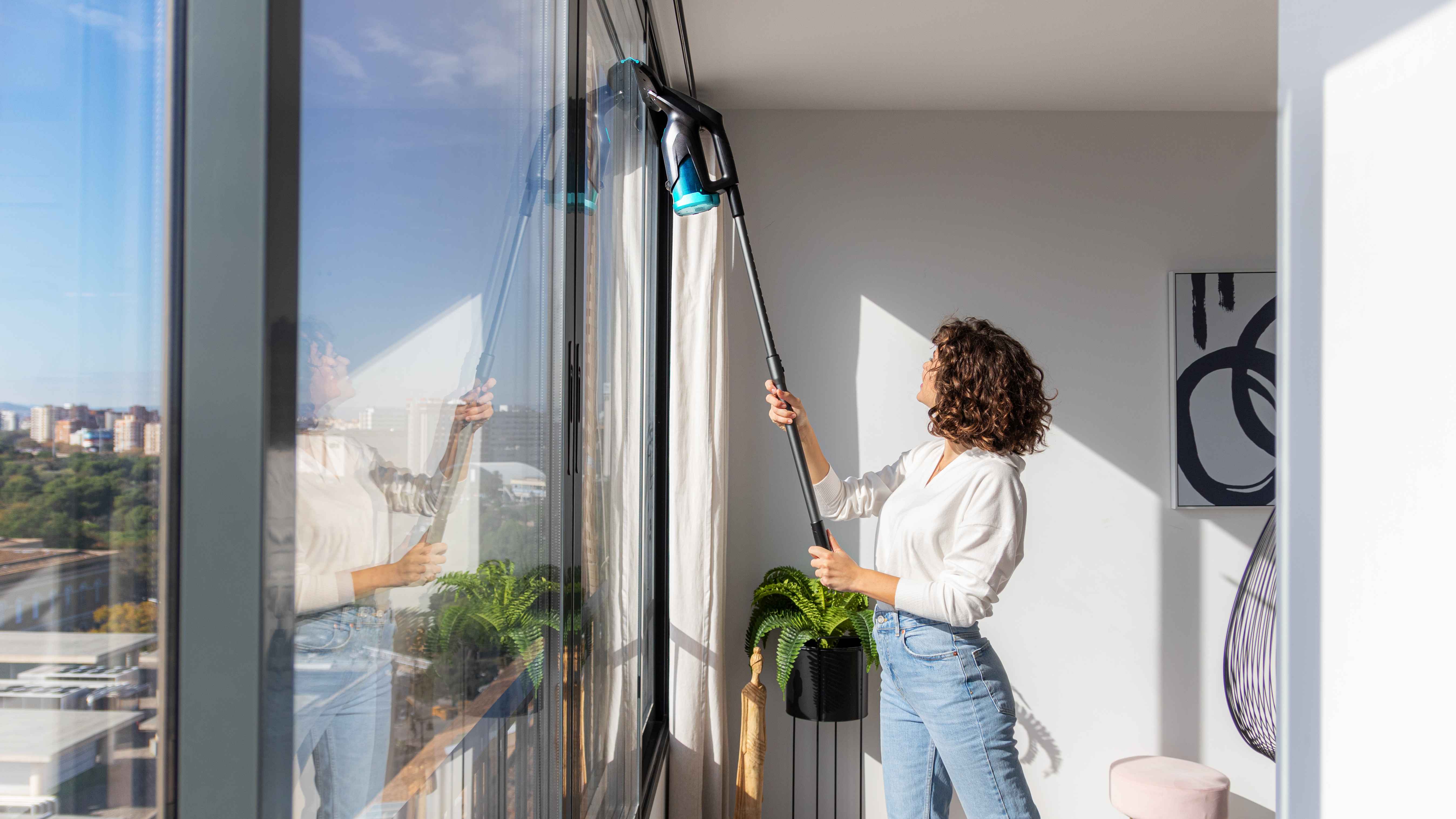 Mujer limpiando una ventana con una herramienta de limpieza.