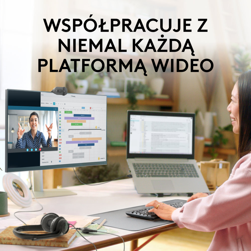 Kobieta przy biurku, korzystająca z monitora i laptopa. Kamera internetowa jest na monitorze.