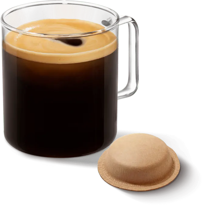 Klarer Glasbecher mit dunklem Kaffee und Schaum, und eine Kaffeekapsel auf schwarzem Hintergrund.