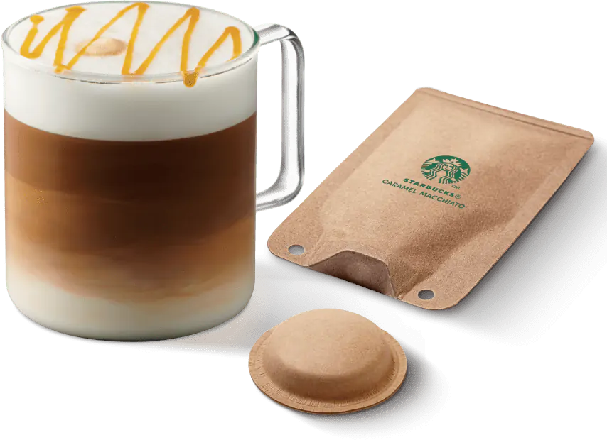Starbucks Caramel Macchiato Getränk im Glas mit Kapsel und Verpackung. Der Hintergrund ist weiß.