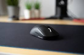 Siyah bilgisayar faresi siyah mousepad üzerinde, bitkilerle bulanık arka plan.