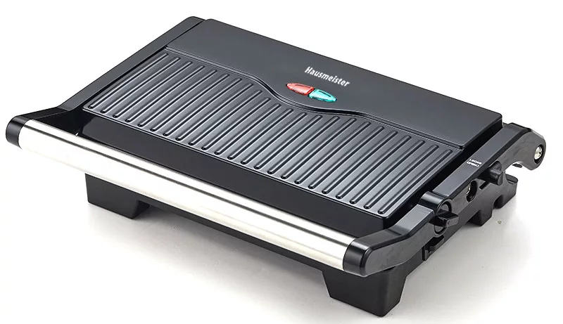 Egy fekete elektromos grill fehér felületen, fogantyúval és vezérlőkkel.