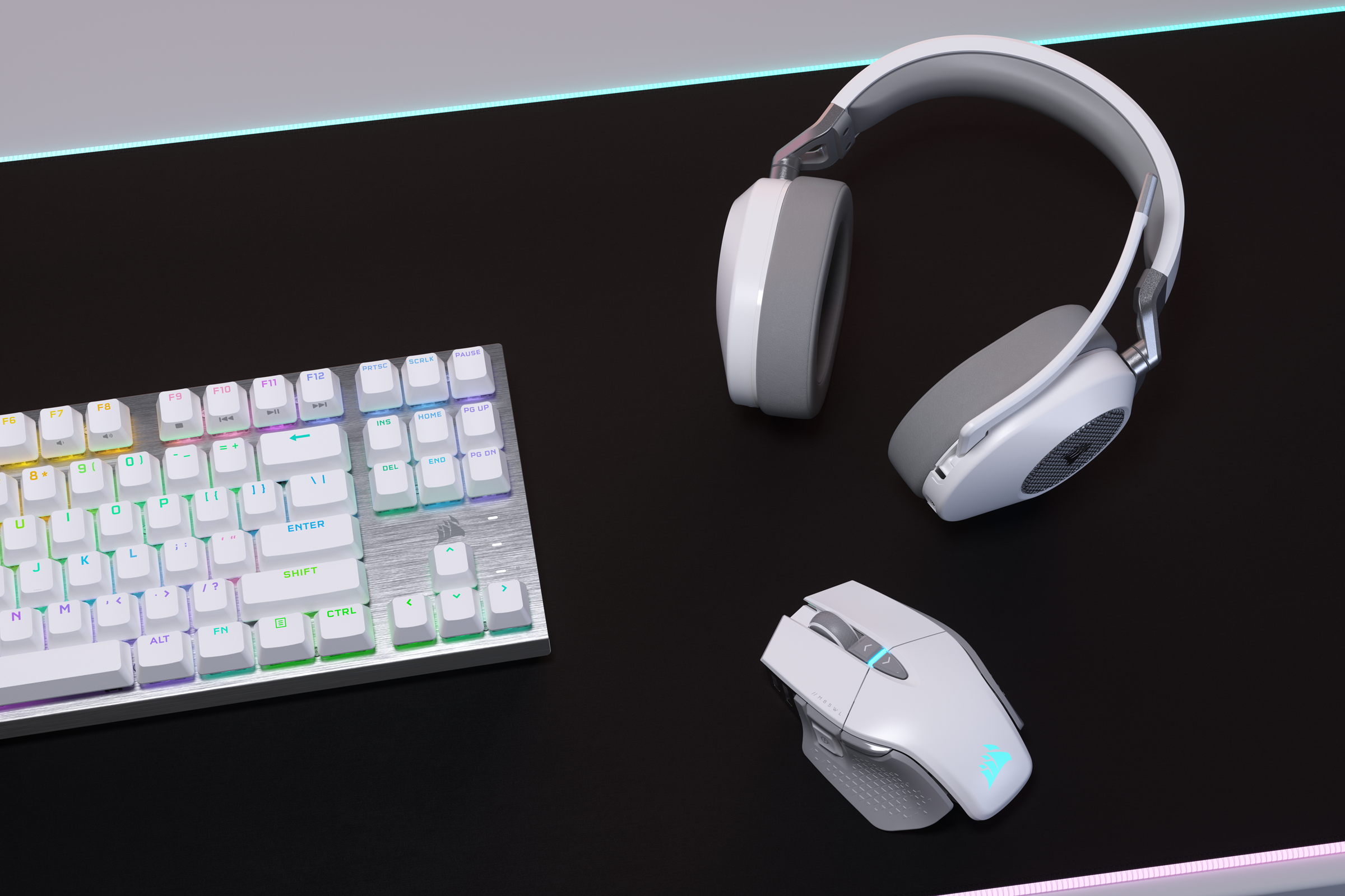 Eine Tastatur, Maus und Kopfhörer, alle in Weiß, auf einer schwarzen Schreibtischoberfläche.