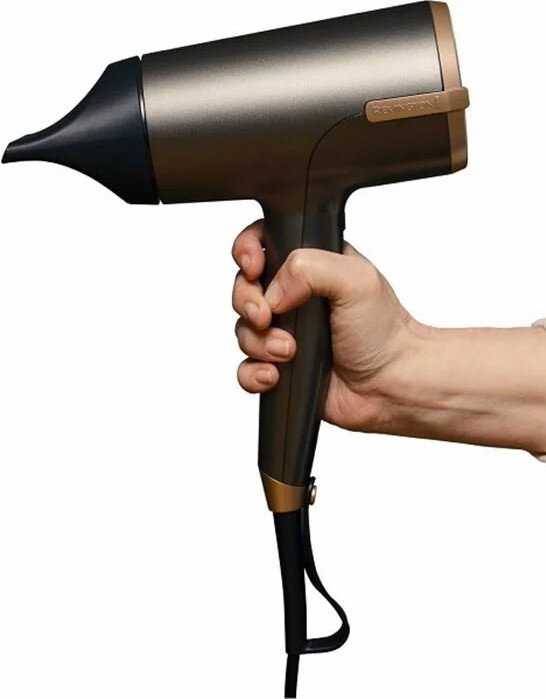 Dłoń trzymająca suszarkę do włosów, z ciemnoszarym i złotym schematem kolorów.