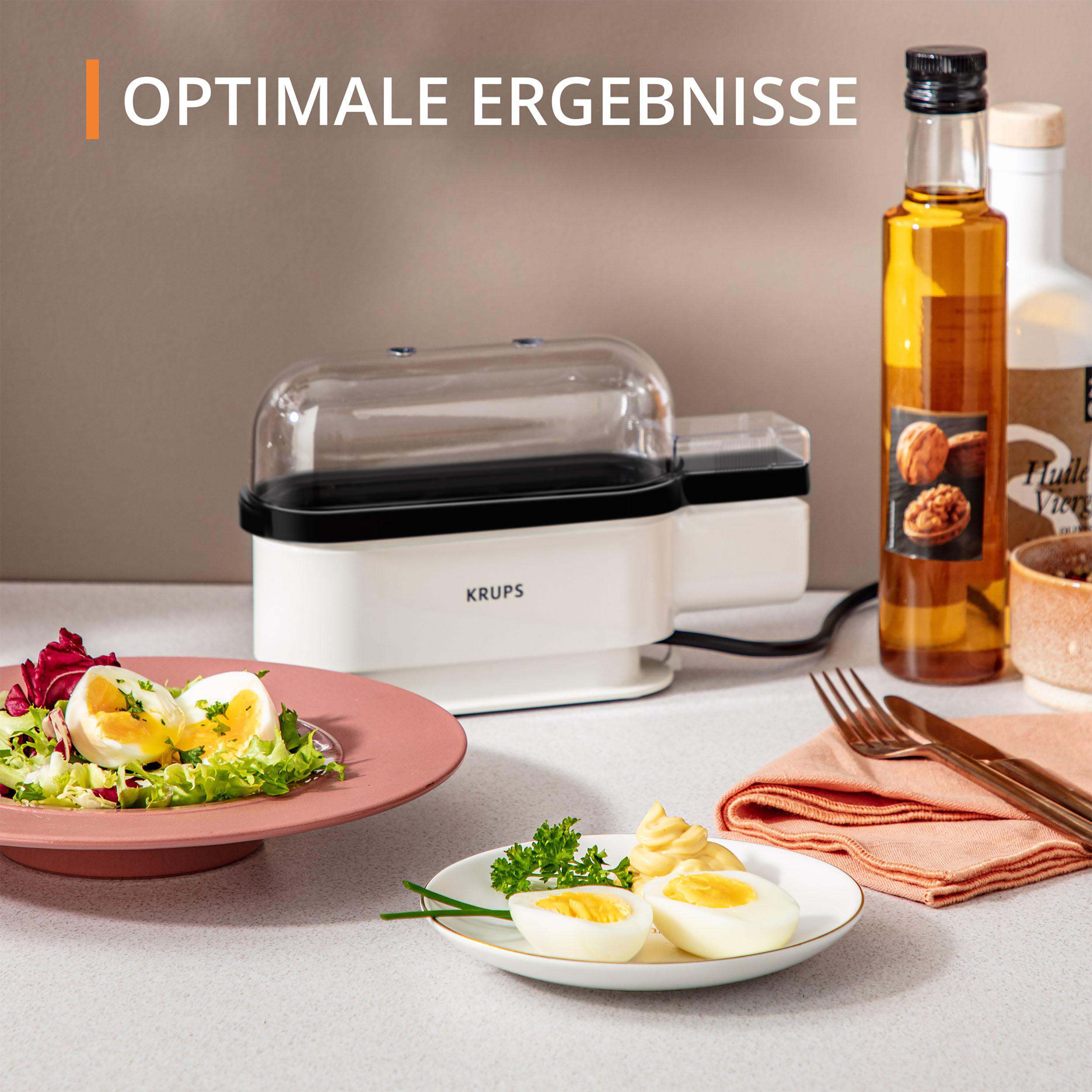 Ein weißer und schwarzer Eierkocher mit Eiern und Salat, zusammen mit Öl und Mayonnaise.