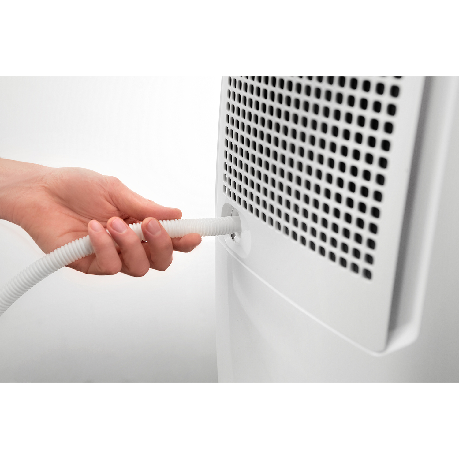 Una mano che inserisce un tubo bianco in un elettrodomestico bianco.