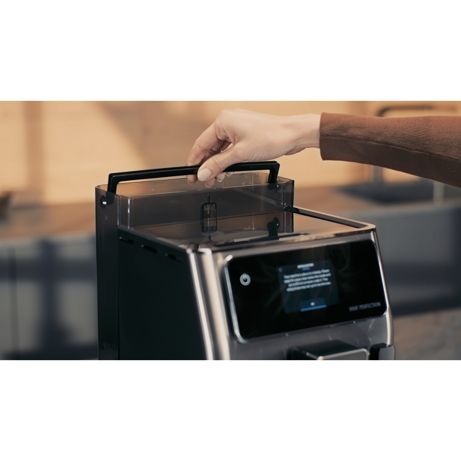A person's hand is pulling up a handle of a black coffee machine.