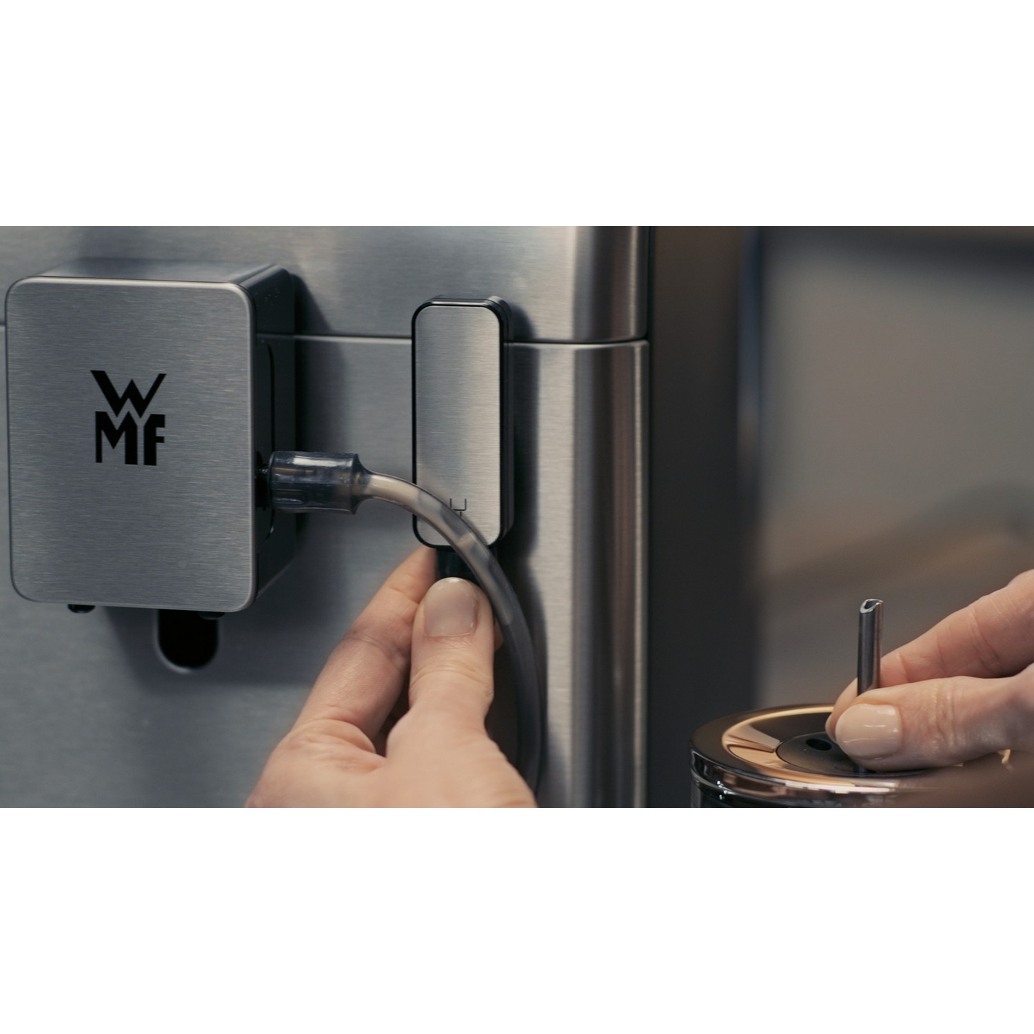 Person's hands near a stainless steel device and accessory. Close up image.