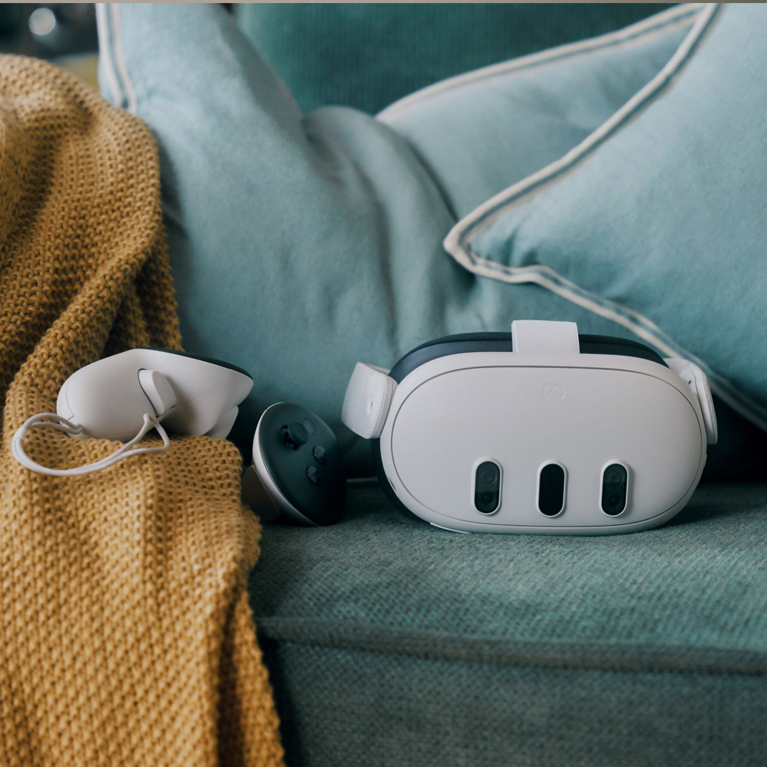 VR headset and controllers on a teal couch with a yellow blanket.