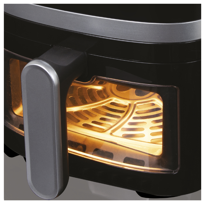 Schwarzer Airfryer-Innenraum mit Kochkorb und leuchtend orangefarbenem Licht.