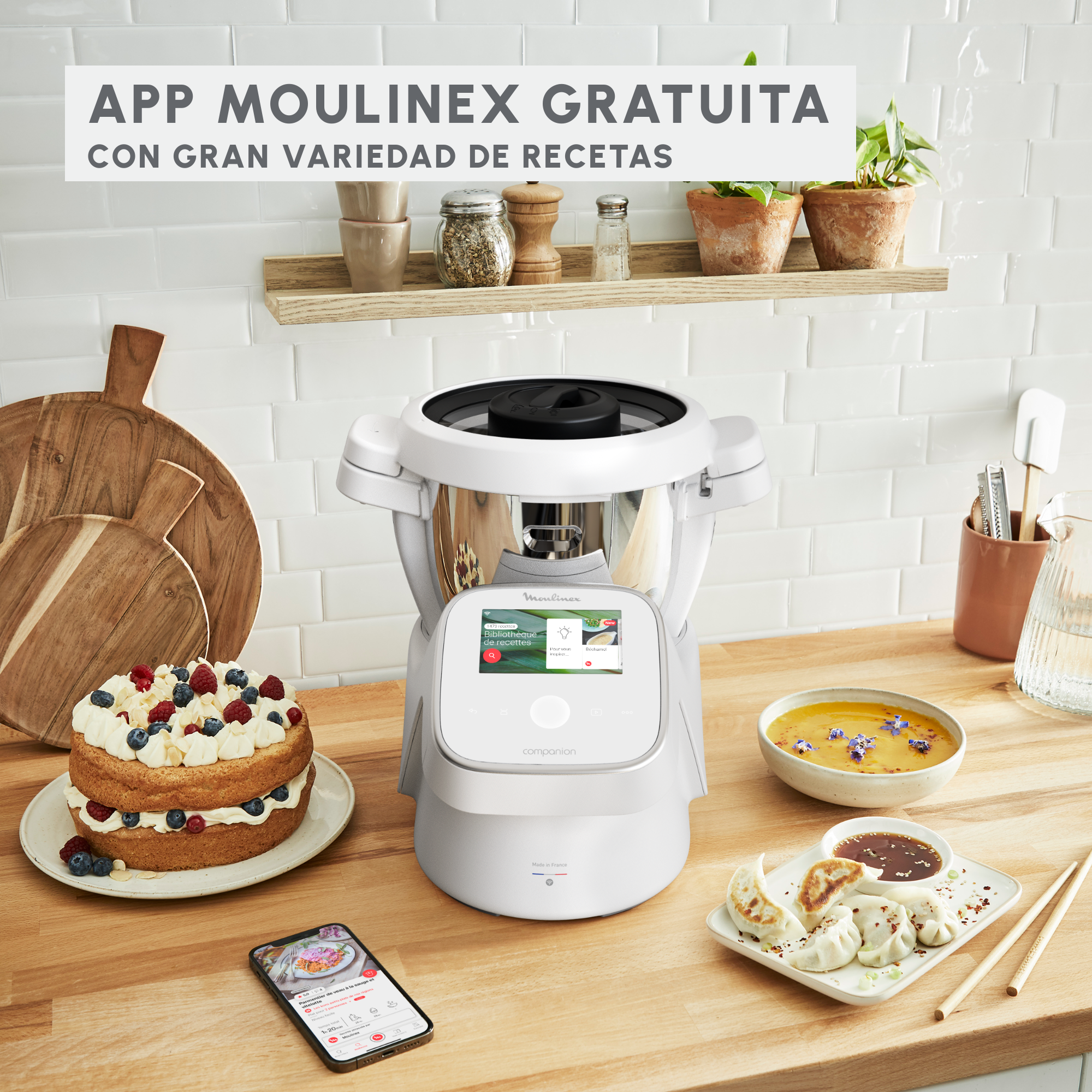 Escena de cocina con robot de cocina Moulinex, pastel y otros platos. Texto: APP MOULINEX GRATUITA.
