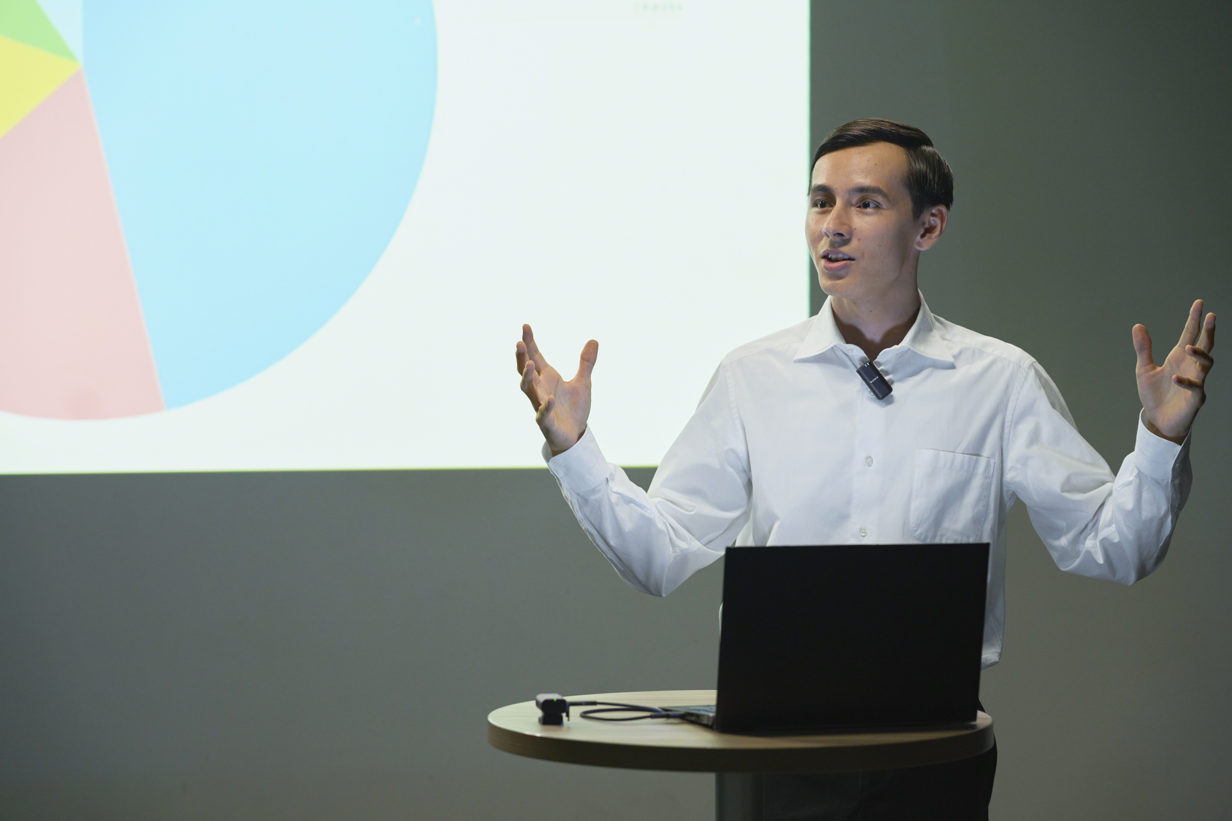 Mann hält Präsentation mit Laptop und Tortendiagramm im Hintergrund.