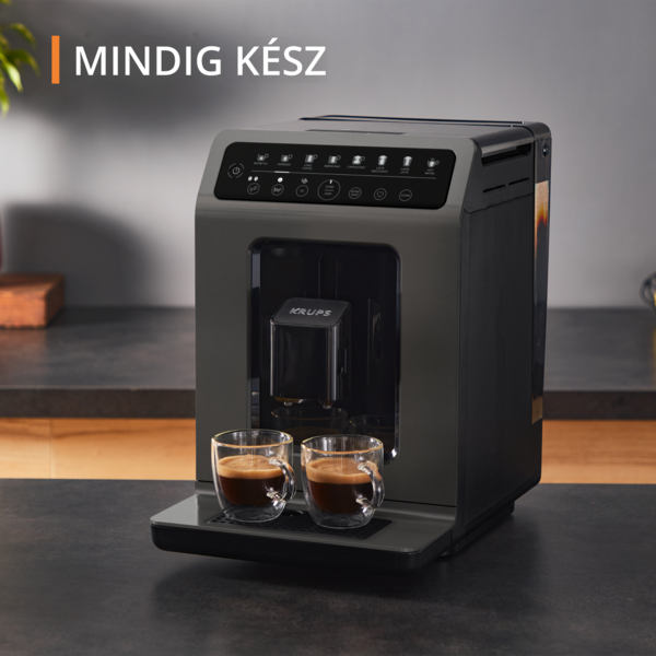 Sötétszürke Krups kávéfőző két üveg kávéscsészével a sötét pulton.