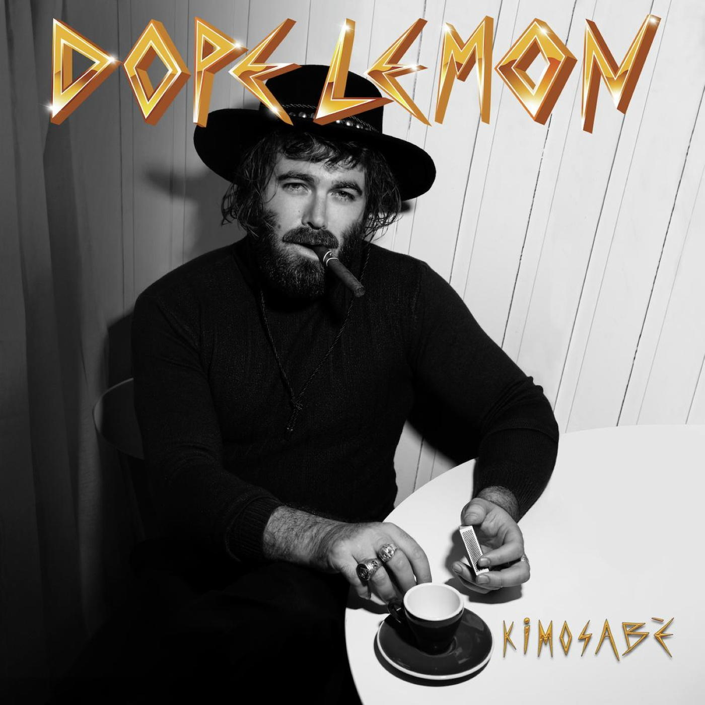 Zwart-wit foto van een man met een hoed die een sigaar rookt.