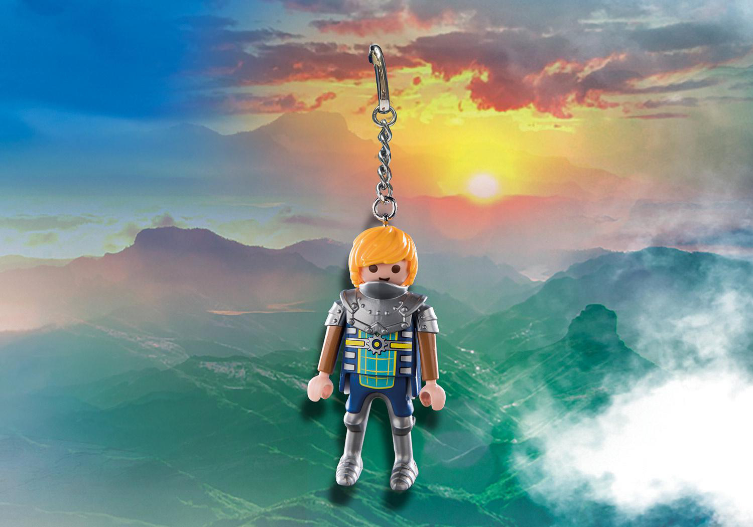 Playmobil-Figur, die an einem Schlüsselanhänger hängt, vor einem malerischen Berg- und Sonnenuntergangshintergrund.