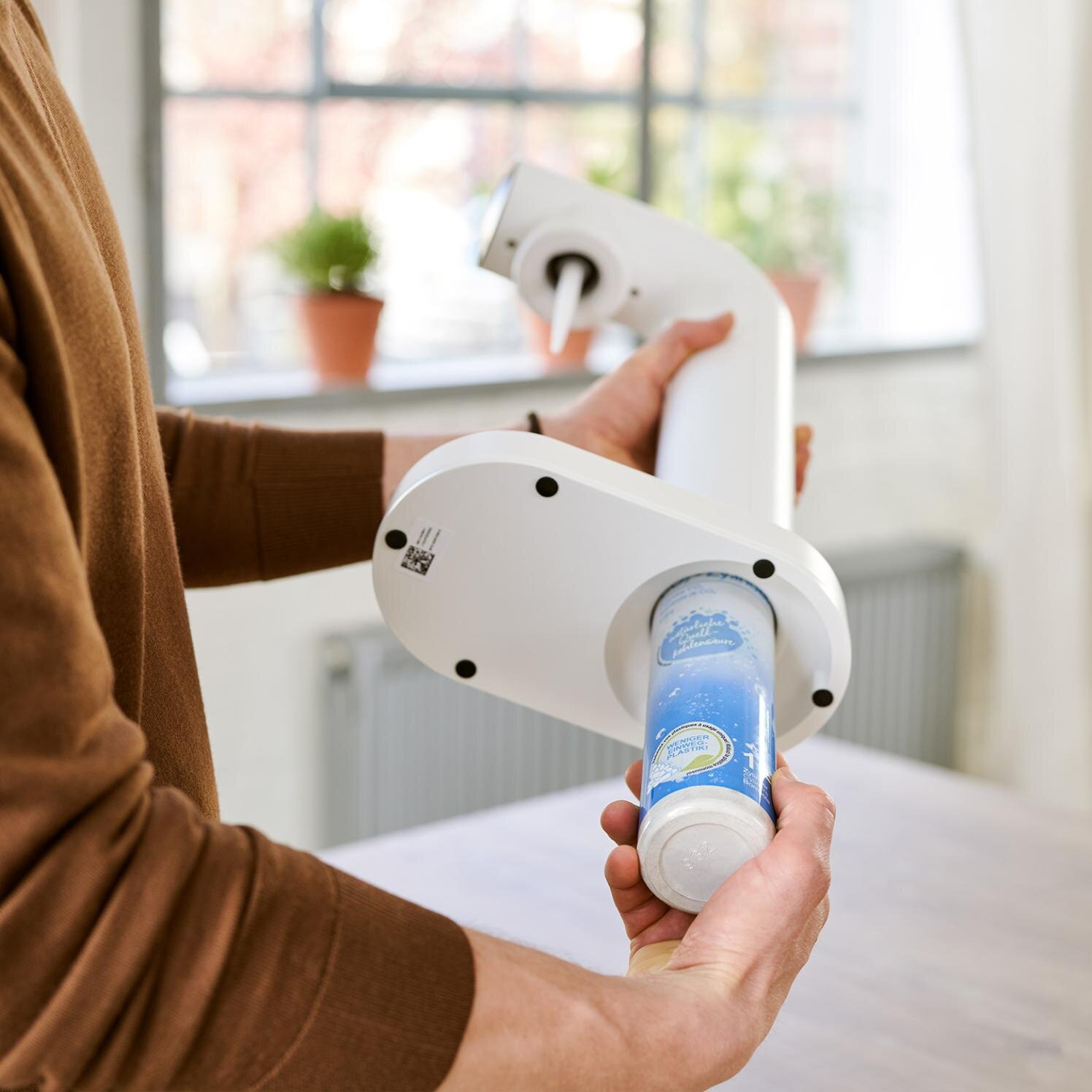 Osoba trzyma biały filtr wody. Filtr jest wkładany. Jasne tło.