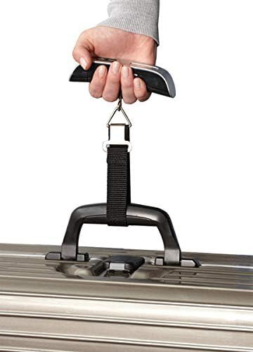 Dłoń trzymająca wagę do bagażu przymocowaną do uchwytu walizki. Białe tło.