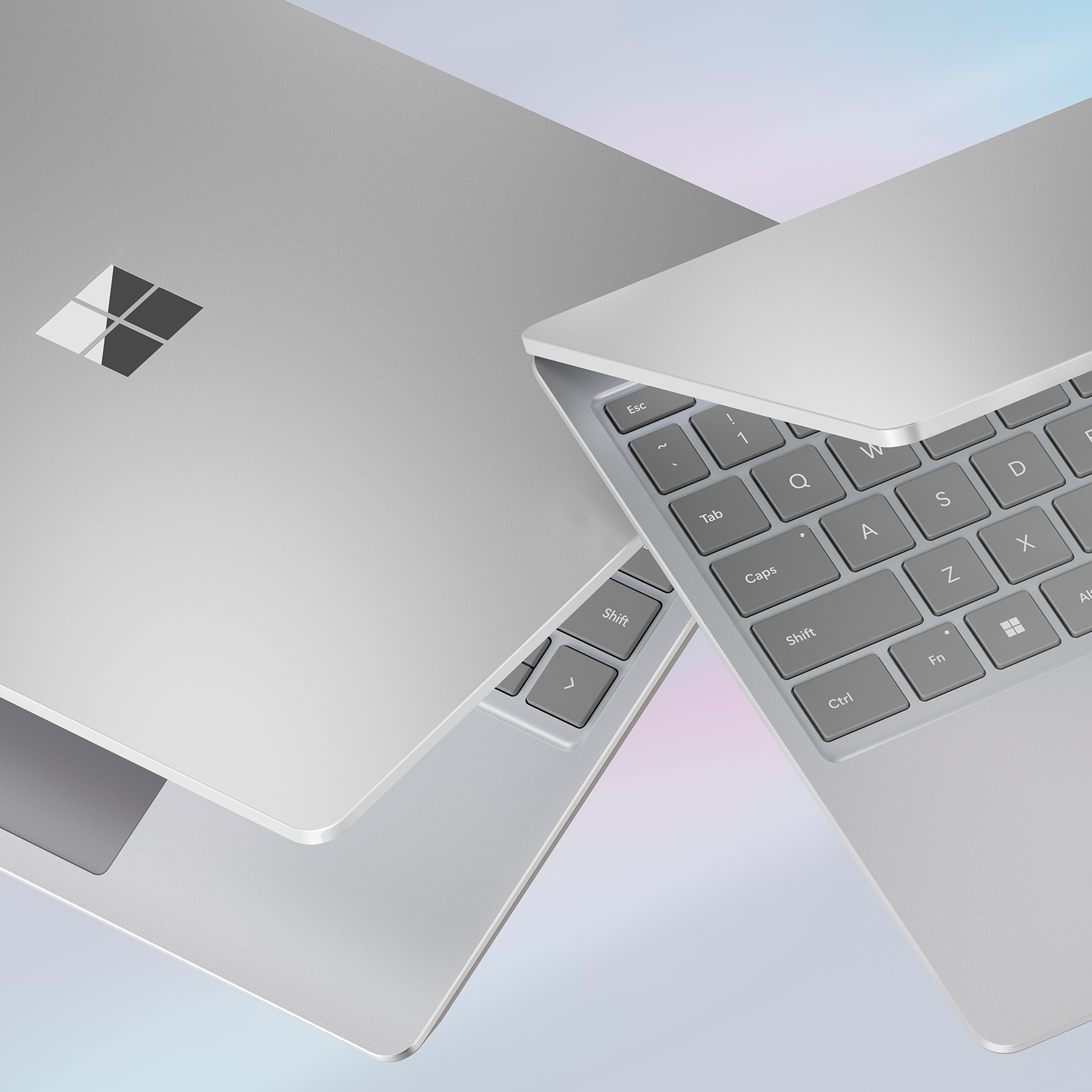 Dos portátiles grises en ángulo, mostrando las teclas del teclado con el logo de Microsoft en la parte superior izquierda.
